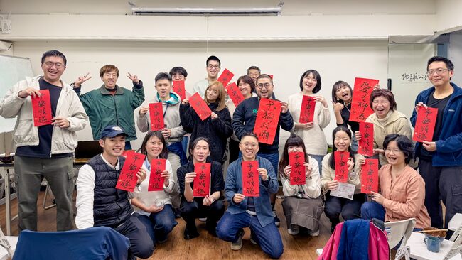 辦公室中，志工們與地球公民的員工舉起春聯開心合照