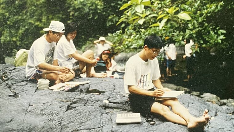 李根政坐在一顆大石頭上寫生