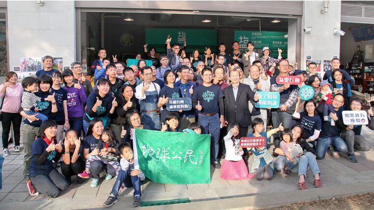 地球公民的夥伴與一群支持者拿著地球公民的旗子合照